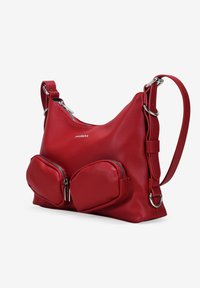 Bolso de hombro de cuero rojo con una textura suave, que presenta dos bolsillos redondeados con cremallera en la parte frontal y una correa ajustable.