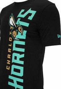 Camiseta de algodón negra con el gráfico "CHARLOTTE HORNETS" en verde azulado y dorado, con un logo de avispa y tipografía en negrita en el frente.