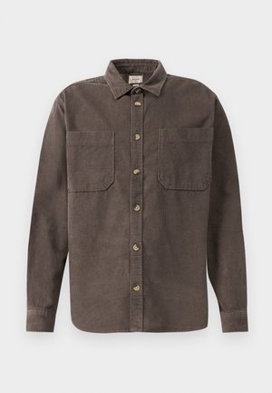 Camicia in corduroy marrone con chiusura a bottoni frontale, due tasche sul petto e maniche lunghe; presenta un tessuto texture e un orlo arrotondato.
