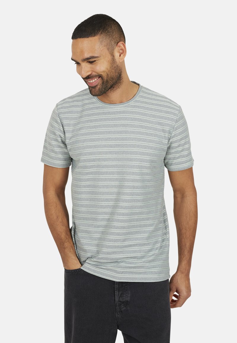 T-shirt à manches courtes rayé en gris clair avec des lignes horizontales plus foncées. Encolure ras du cou, tissu doux, coupe décontractée, fente sur le bas sur les côtés.