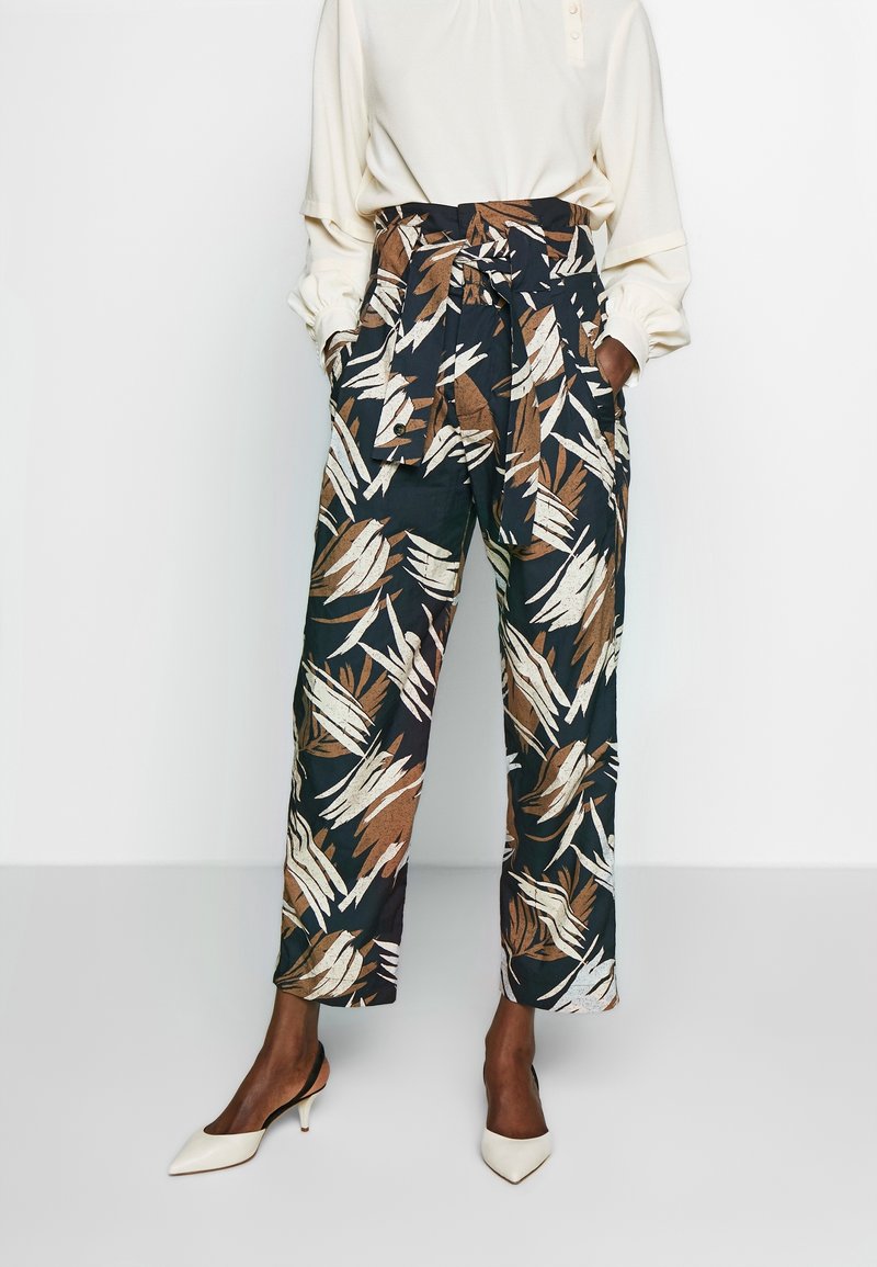 Luftiga, marinblå byxor med ett lövmönster i brunt och beige, med ett knyt i midjan, vida ben och fickor, som matchas med spetsiga vita klackar.