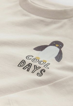 Gaišais beigu T-krekls ar pingvīna grafiku un tekstu "COOL DAYS" melnā krāsā. Mīksts kokvilnas materiāls ar klasisku apaļu kakla izgriezumu.