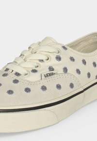 Κρεμ παπούτσι Vans με μπλε κεντημένα λουλούδια, λευκά κορδόνια και μαύρη ρίγα σε πάτο από παχύ καουτσούκ.