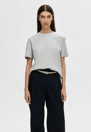 Graues T-Shirt mit kurzen Ärmeln aus Baumwolle, lässiger Schnitt. Kombiniert mit weiteren navyfarbigen Hosen und einem hellen Gürtel.