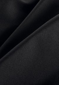 Tessuto nero intrecciato con una texture liscia, caratterizzato da un motivo sottile e costante di linee fine. Il materiale sembra resistente e flessibile.