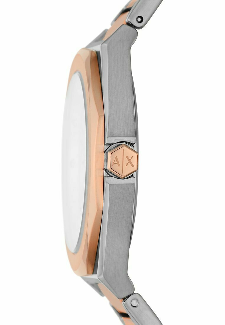 Reloj octagonal con caja de acero inoxidable plateado y acentos en oro rosa. Presenta una superficie texturada y una corona hexagonal con marca.