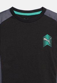 Μαύρο μπλουζάκι με στρογγυλή λαιμόκοψη, γκρι πάνελς στους ώμους και λογότυπο Puma με τυρκουάζ λεπτομέρειες στο αριστερό στήθος.