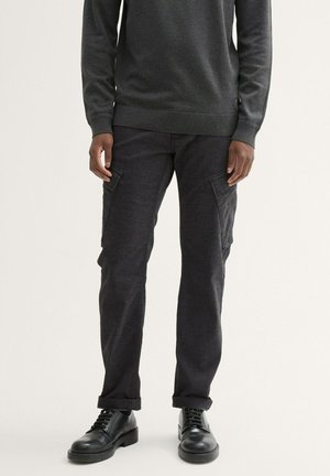 Gray sweatshirt with long sleeves and ribbed cuffs, paired with dark gray cargo pants featuring side pockets and a straight cut. Black shoes.