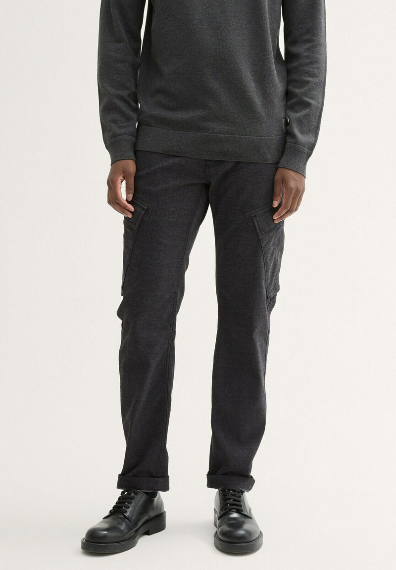 Grijze sweatshirt met lange mouwen en geribde manchetten, gecombineerd met donkergrijze cargobroek met zijzakken en een recht model. Zwarte schoenen.