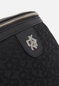 Černá zipová taška s texturovaným vzorem a stříbrným logem. Hladký materiál s kontrastními akcenty.
