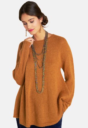 Rustfarbener Strickpullover mit rundem Halsausschnitt, lockerem Schnitt und gerippten Bündchen. Eine mehrfarbige Perlenkette in Schichten sorgt für zusätzliche Details.