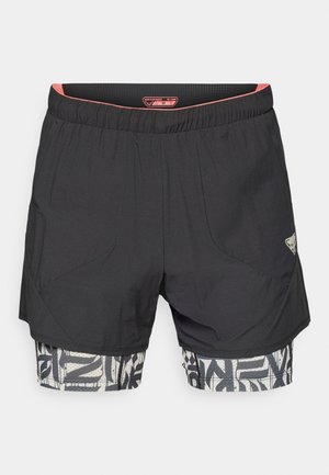 Zwarte sportshorts met een elastische tailleband, met een gestructureerde bovenlaag en een gemusterde ondersectie in wit en zwart.