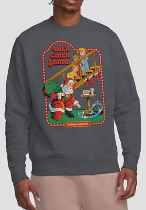 Three children spying on Santa near a staircase with a milk glass, cookie plate, and a bear trap beneath him. Text: "Let's Catch Santa."