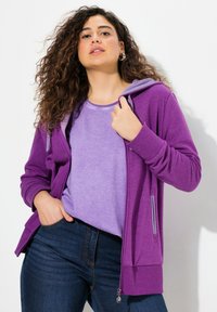 Felpa viola con zip abbinata a una maglietta leggera viola. La felpa presenta una vestibilità comoda, tasche frontali e polsini a costine.