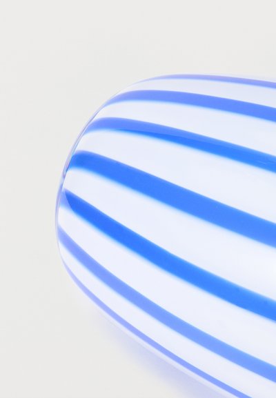 Στρογγυλό λευκό αντικείμενο με ομοιόμορφα κατανεμημένες κάθετες μπλε ρίγες σε ανοιχτό φόντο, με κοντινή λήψη της καμπυλωτής του επιφάνειας.