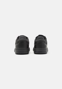 Sorte læder sneakers med en glat finish, polstret krave, teksturerede detaljer og en robust gummisål. Brandnavnet "HUGO" prægede på hælen.