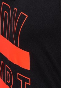 Černé tričko s velkým tučným červeným písmem, které zobrazuje slovo "READY", a s akcentním pruhem přes hrudník. Měkká látka, ležérní design.