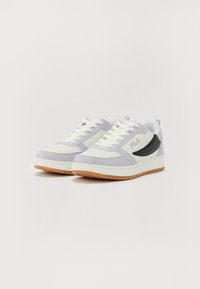Grå og hvite sneakers med svarte detaljer, med en teksturert såle og snøring. Logo vist på siden og hælen.