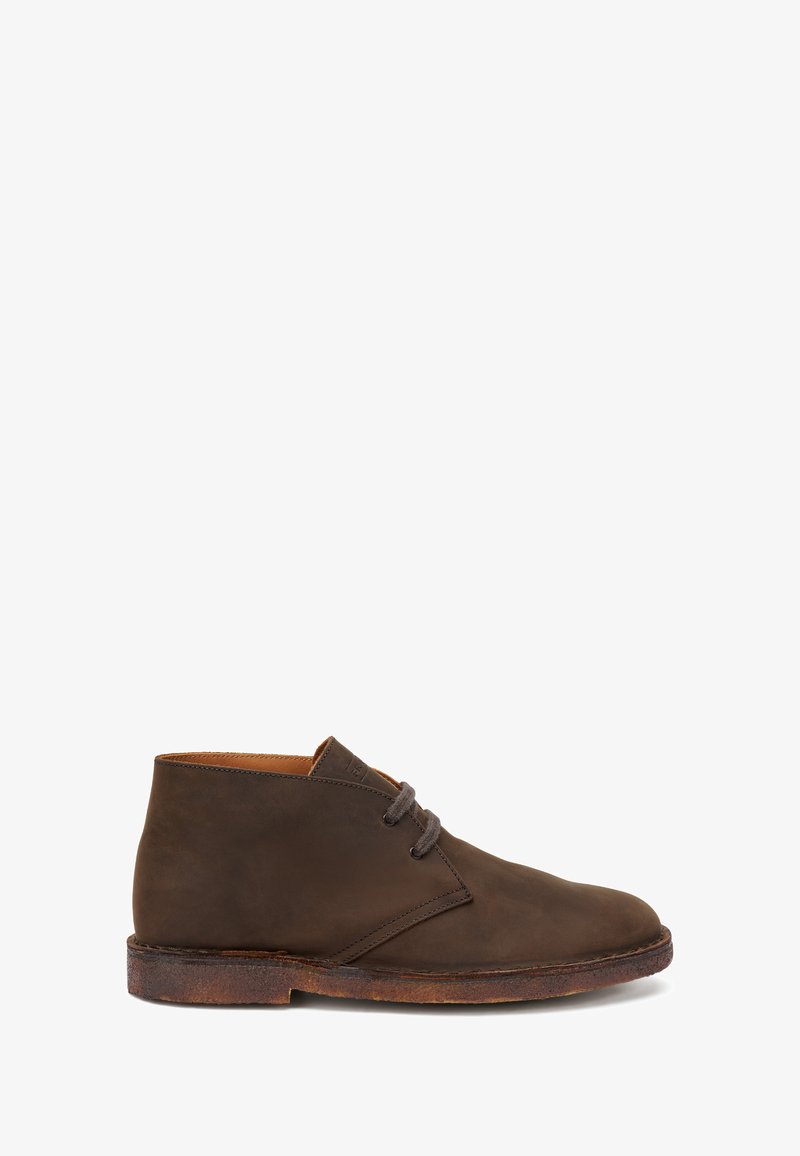 Stivaletto chukka in pelle marrone con due occhielli, punta tonda, suola in crepe e cuciture minimali, mostrato di profilo su sfondo bianco.
