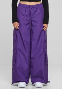 Lila, weit geschnittene Cargo-Hosen mit elastischem Bund, mehreren Seitentaschen und Kordelzugabschlüssen, aus leichtem, glattem Stoff.