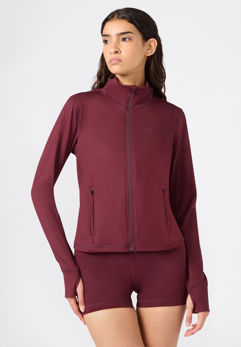 Bordeaux sportjack met hoge kraag, lange mouwen en ritszakken. Soepele textuur, getailleerd ontwerp, gecombineerd met bijpassende shorts.