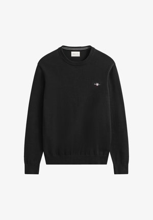 Crni pulover s okruglim izrezom od pletiva, s malim izvezenim logotipom na prsima. Manžete i rubovi su rebrasti za uski oblik.