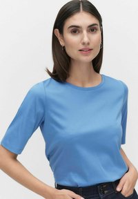 Blå kortärmad t-shirt med rund halsringning, tillverkad av mjukt tyg. Bärs med mörka jeans och har en avslappnad passform.