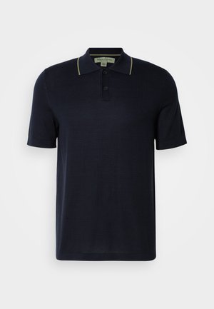 Marineblaues Poloshirt mit kurzen Ärmeln, zwei Knöpfen und dezentem beigefarbenen Saum am Kragen, vor einem einfarbigen hellen Hintergrund präsentiert.