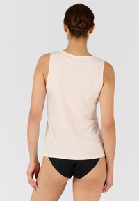Top senza maniche di un delicato rosa chiaro, con scollatura tonda, texture liscia e una vestibilità casual, abbinato a slip neri.