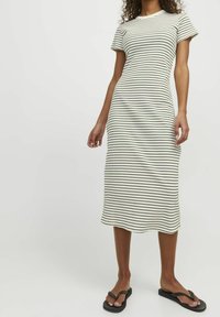 Robe midi rayée en crème avec des rayures horizontales noires. Elle possède des manches courtes, un col rond et une silhouette ajustée.