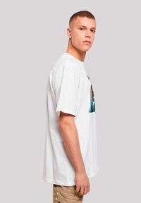 White cotton t-shirt with short sleeves, featuring a colorful graphic design on the front. Relaxed fit, smooth texture.