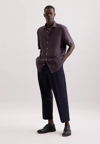 Donkerpaars linnen overhemd met korte mouwen en knopen, gecombineerd met losse navy broek en zwarte nette schoenen, gedragen door een staand model.