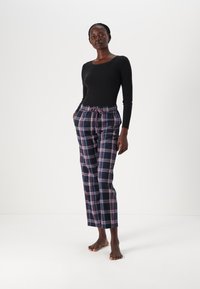 Black long-sleeve shirt paired with plaid trousers in navy, pink, and white. Trousers have an elastic waistband and pockets.