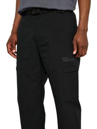 Bărbat purtând pantaloni cargo negri cu buzunare laterale și o curea integrată, arătând mâinile odihnindu-se pe lângă corp.