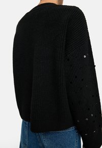 Czarny sweter dzianinowy o prążkowanej fakturze, z szerokimi rękawami ozdobionymi cekinami i skróconym krojem w talii.