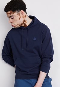 Dunkelblauer Kapuzenpullover mit Kängurutasche, gerippten Bündchen und einem kleinen Logo-Aufnäher auf der Brust. Weicher Stoff mit lässiger Passform.