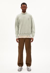 Lichtgroene sweatshirt met een ronde hals en een kleine sleutelgatgrafiek, gecombineerd met brown cargobroek met zijzakken en een ontspannen pasvorm.