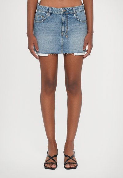 Denim-Miniröck mit einem hellblauen Washed-Look, ausgefranstem Saum, Fünf-Taschen-Design und Knopfverschluss. Kombiniert mit schwarzen Riemchensandalen.