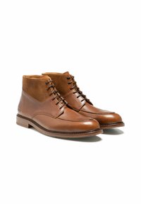 Bottines en cuir marron avec des accents en daim, bout rond et détails de lacets. Elles présentent une finition lisse et une semelle en bois.