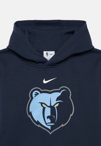 Hanorac bleumarin cu buzunar tip kangur. Are un logo cu un urs în nuanțe de albastru deschis și gri, cu ochi galbeni. Logo-ul Nike este plasat deasupra.