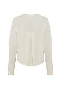 Haut beige clair à manches longues avec une texture douce, présentant un ourlet arrondi et un dos plissé. Style simple et discret.