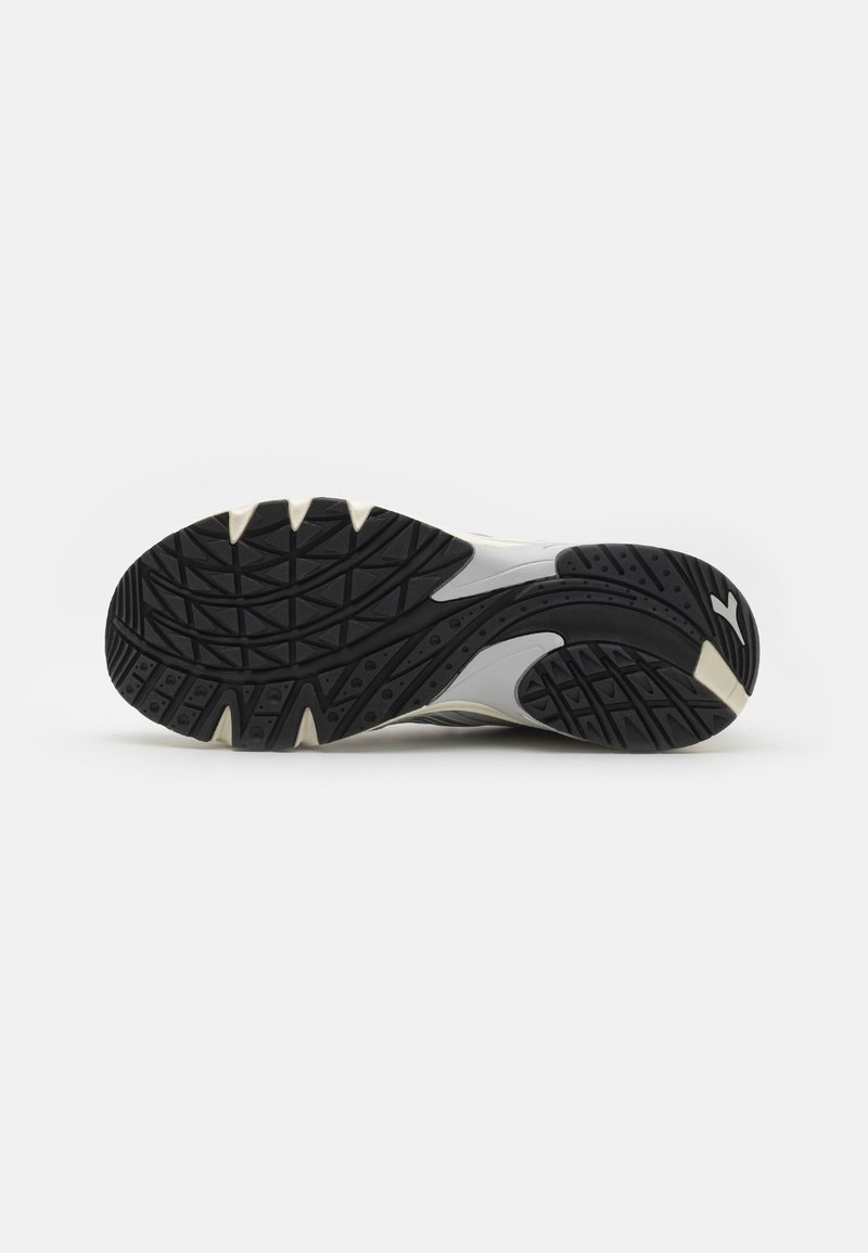 Zool van een zwart-witte sport schoen met gedetailleerde loopvlakken voor grip op een effen witte achtergrond.