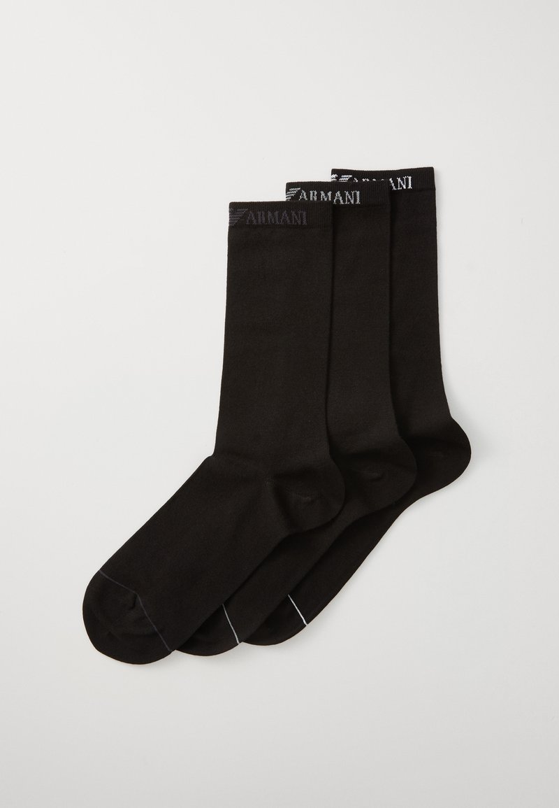 Črne bombažne nogavice do gležnjev, ki imajo rebrast rob in diskretno blagovno znamko na vrhu. Prikazane so tri pare z gladko teksturo.