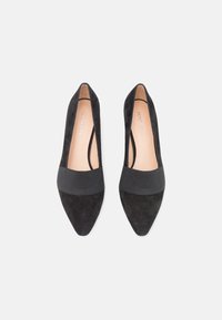 Black suede high heels with a pointed toe and elastic band across the midfoot. Soft texture with a simple, streamlined design.