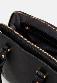 Sac à main en cuir noir avec extérieur texturé et fermeture éclair dorée. L'intérieur comprend une doublure en tissu rayé et plusieurs poches pour l'organisation.