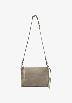 Sac bandoulière en daim beige avec sangle réglable, fermeture éclair et accents de pompons sur fond blanc.