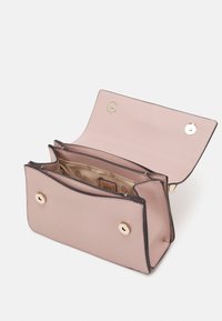 Bledě růžová syntetická peněženka se zlatým kováním, dvěma západkovými knoflíky a texturovaným povrchem. Interiér má béžovou podšívku s logem.