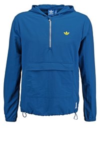 Modrý lehký pulovr s kapucí, přední kapsou a půl zipem, s malým žlutým logem na hrudi a elastickými šňůrkami na spodním lemu.