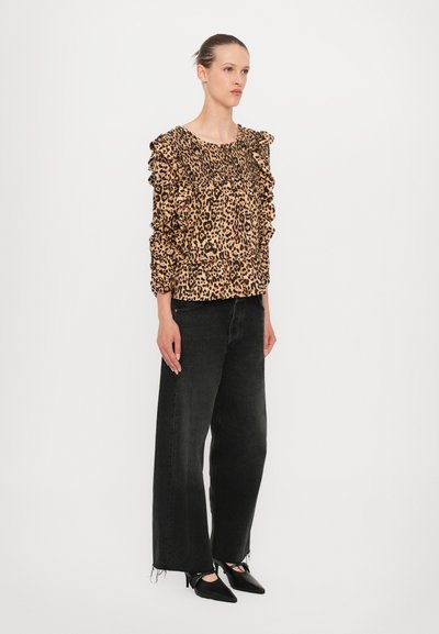 Blouse met luipaardprint en ruches aan de mouwen, gecombineerd met wijde zwarte jeans en puntige zwarte hakken. Textiel met textuur en geplooide details.