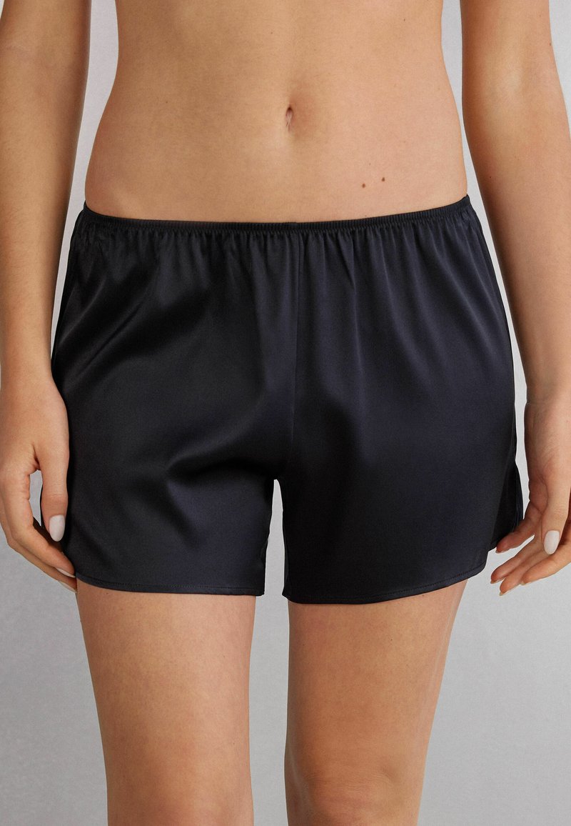 Zwarte satijnen shorts met een elastische tailleband, met een gladde textuur en een losse pasvorm, eindigend boven de midden-dij.